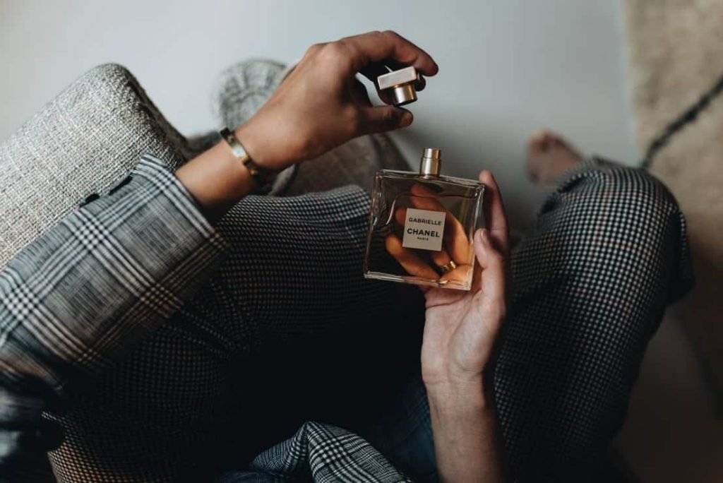 خانمی نشسته با عطری در دست از میان عطرهای معروف و محبوب